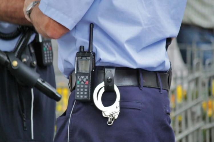 Cintura de un jefe de seguridad con esposas y un 'walkie-talkie' colgado del cinturón; camisa azul celeste y pantalón azul oscuro.