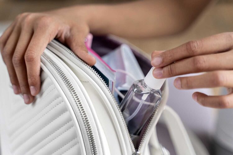 una mujer introduce un perfume en su bolso