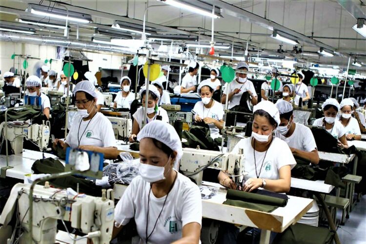 Mujeres filipinas con mascarilla blanca, camiseta blanca y gorro blanco trabajan en fábrica textil