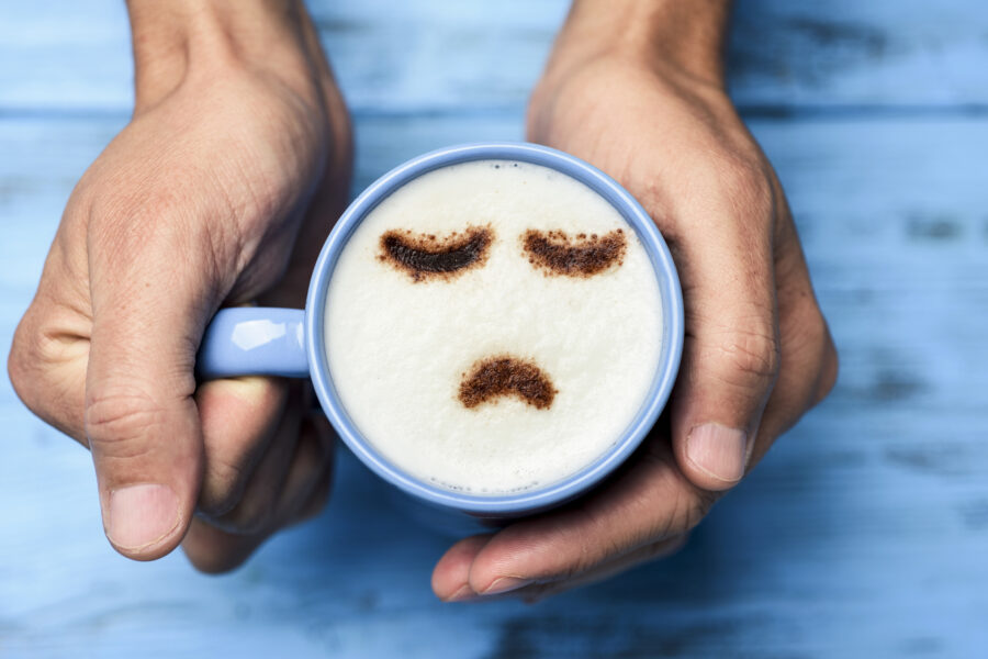 man with a cup of cappuccino with a sad face